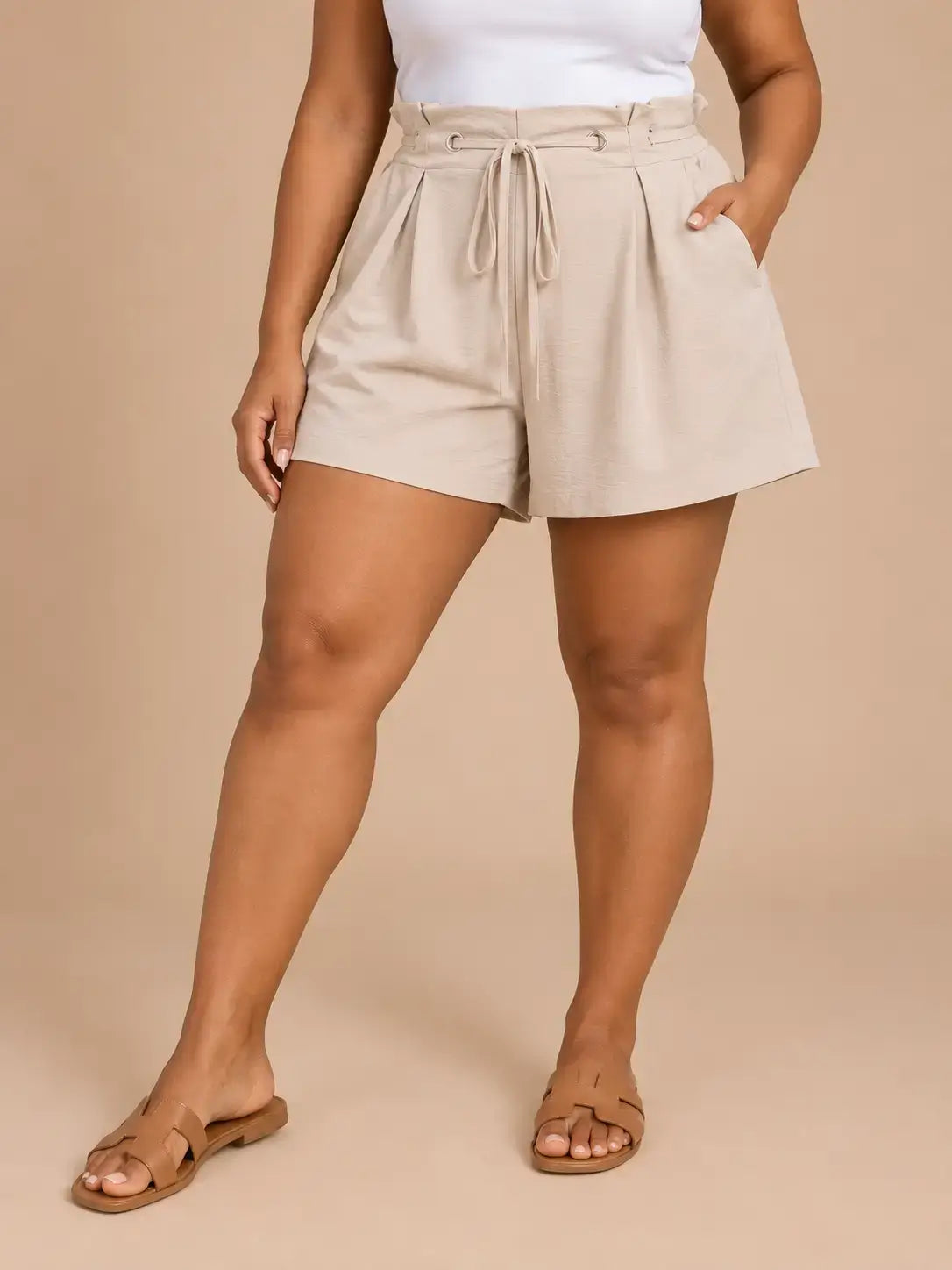 Short Cashia Arezzo beige en talla XL, de cintura alta con cordón ajustable y corte holgado, en medio plano inferior con las piernas separadas.
