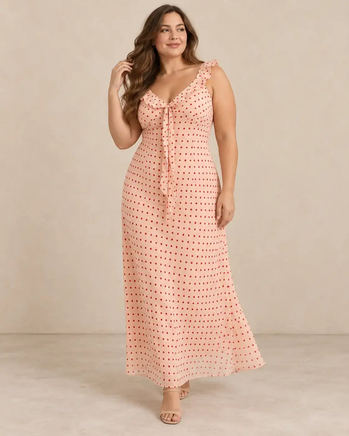 Modelo Cashia talla L con vestido largo rosa de lunares rojos, tirantes con volantes, lazada delantera y caída recta.