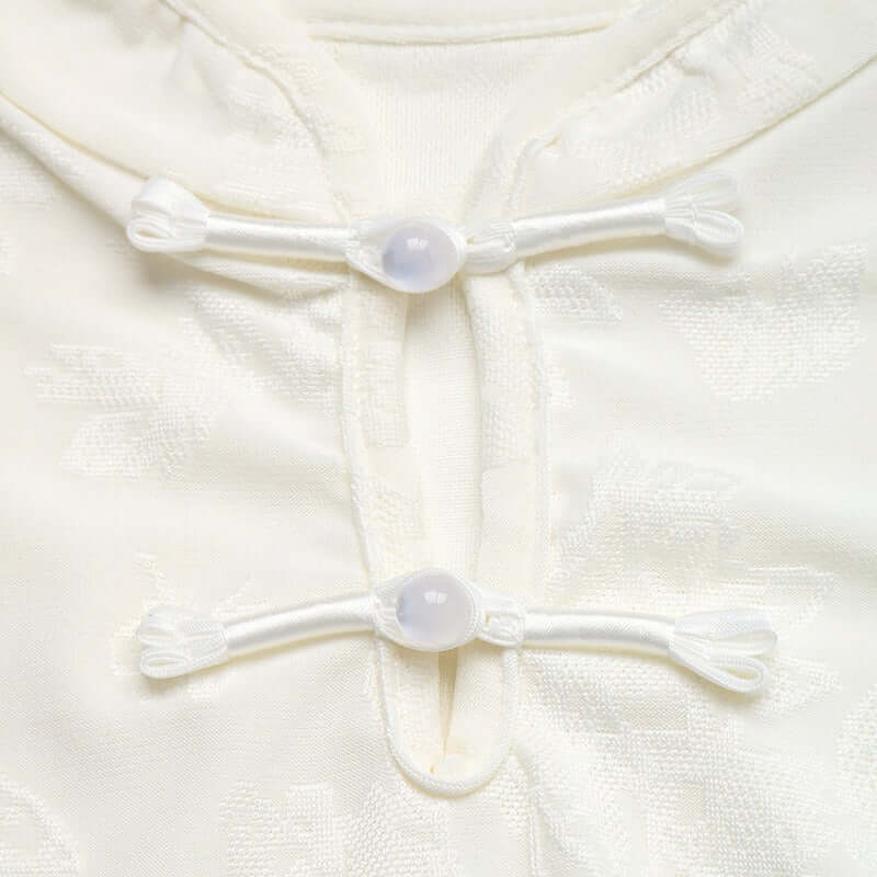 Detalle de los cierres de la camiseta mujer cuello mao detalle floral en color blanco.