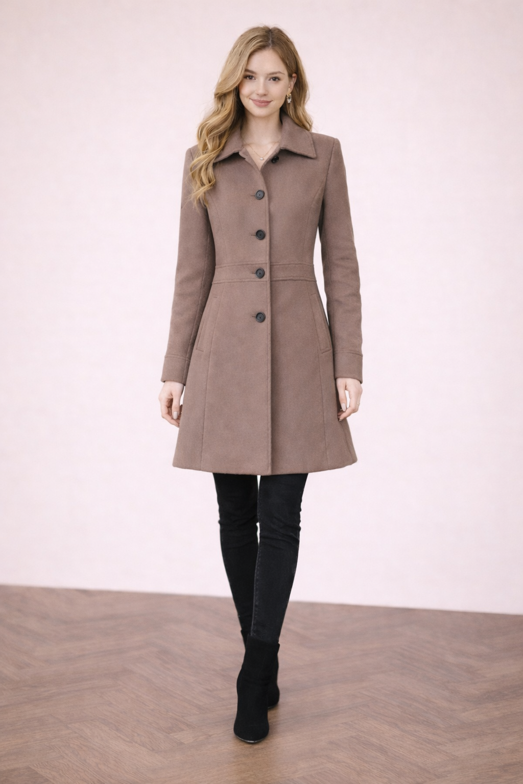 Abrigo Cashia Berlín color coffee brown de algodón, frontal cuerpo entero abotonado, modelo femenina sobre fondo nude con suelo parquet marrón, estilo elegante y ajuste entallado.