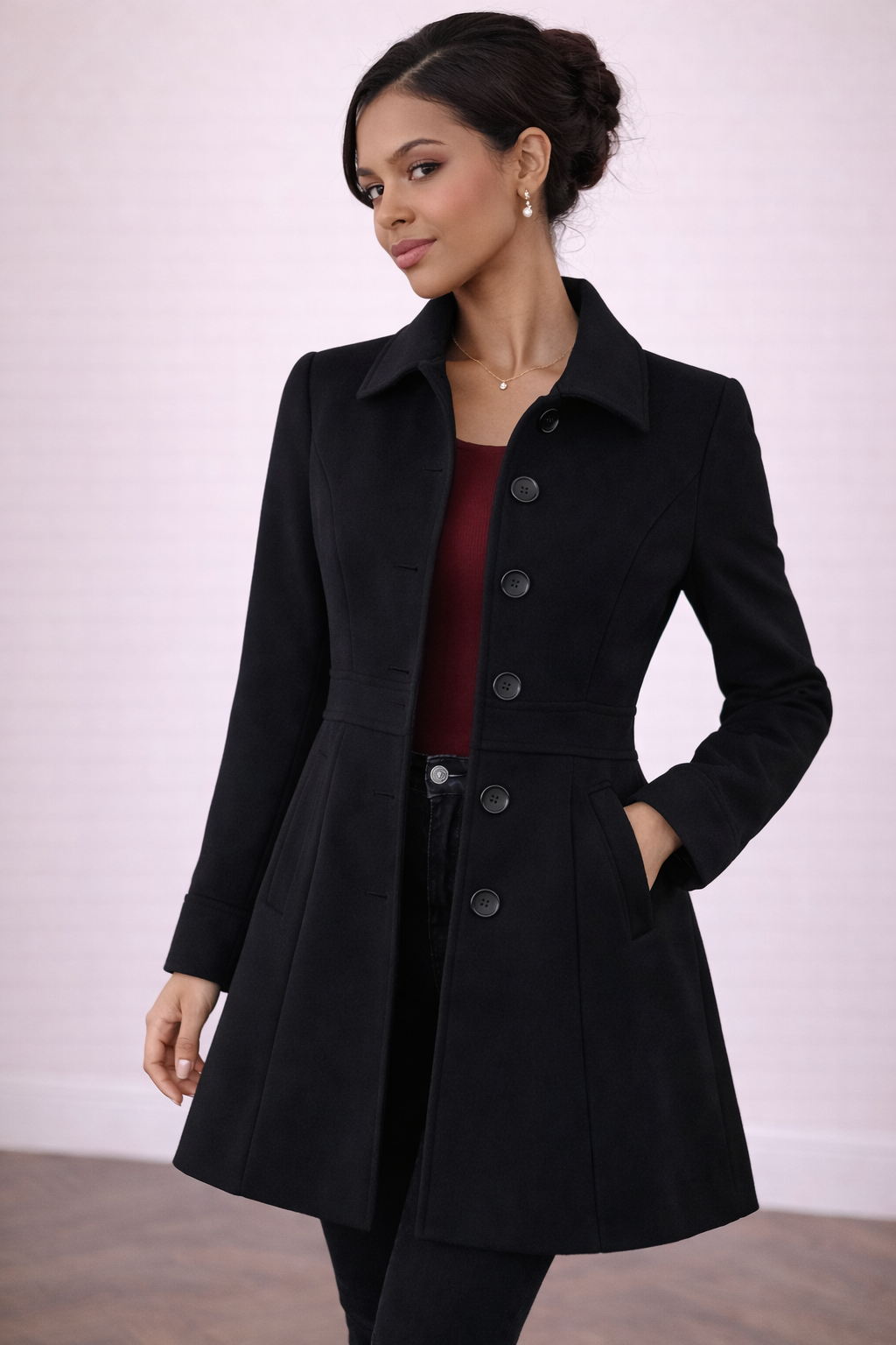 Abrigo Cashia Berlín color negro con cinco botones frontales, medio plano frontal, corte entallado y largo medio, modelo femenina sobre fondo nude con suelo parquet marrón, estilo elegante y premium.