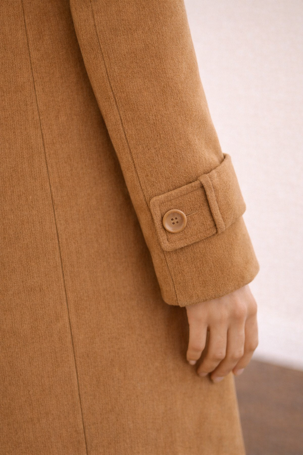 Detalle del puño del abrigo Cashia City en color camel con acabado limpio y tejido estructurado.