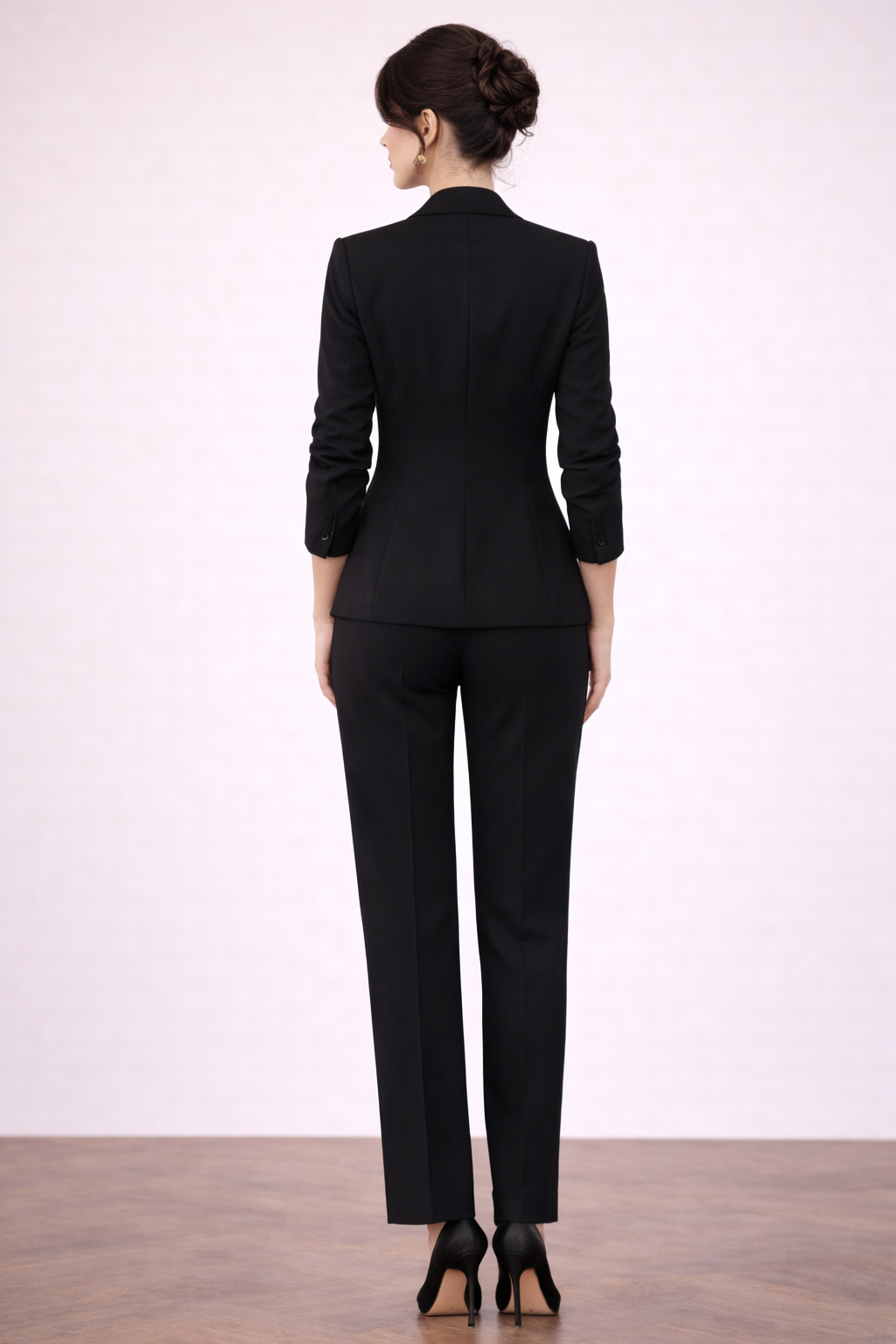 Blazer Cashia Helena en color negro con un botón y bolsillos vivos sin solapa, vista trasera de cuerpo entero combinado con pantalón negro de sastre.