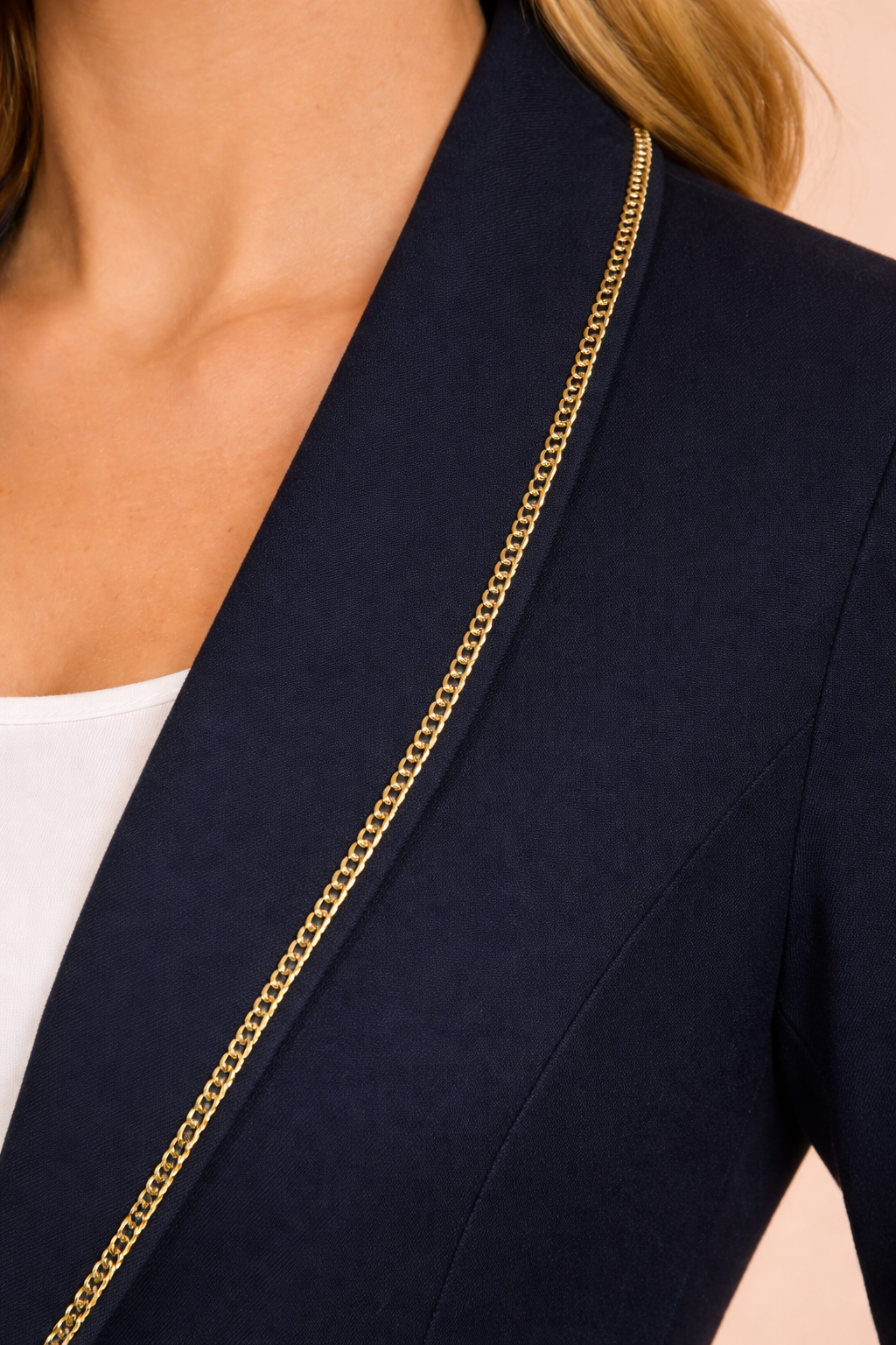 Detalle de la solapa del Blazer Cashia Sofía azul marino con ribete dorado en el borde, mostrando el acabado elegante sobre fondo nude.