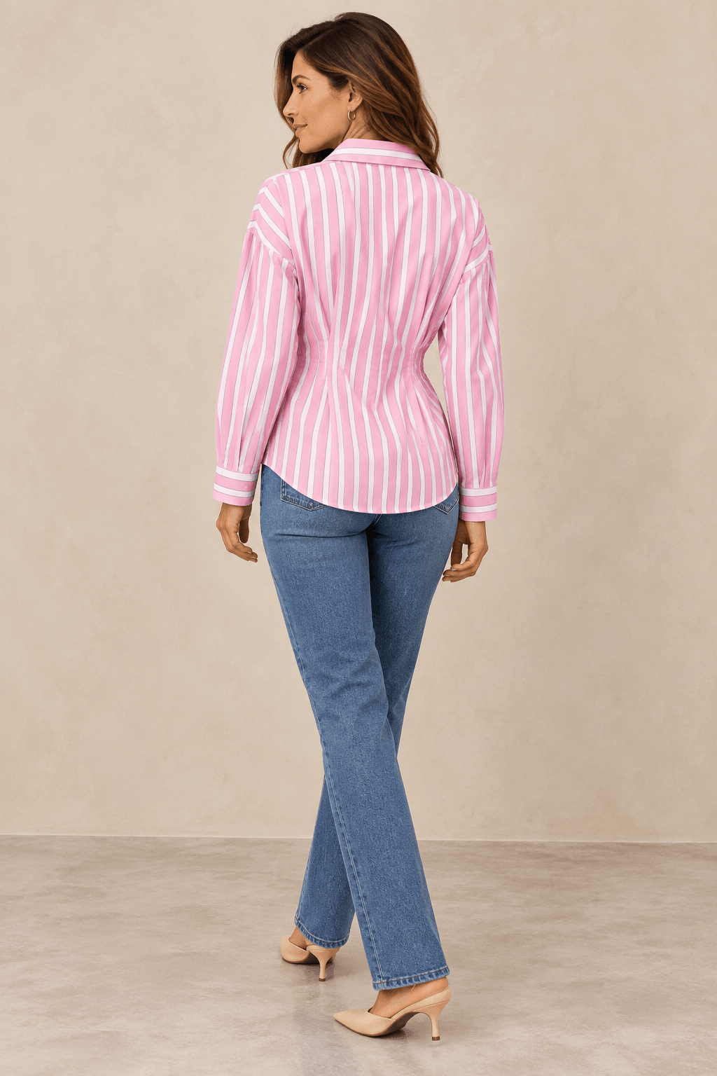 Modelo morena de espalda con Camisa Cashia Clara de rayas rosas y blancas, manga larga y cintura entallada.
