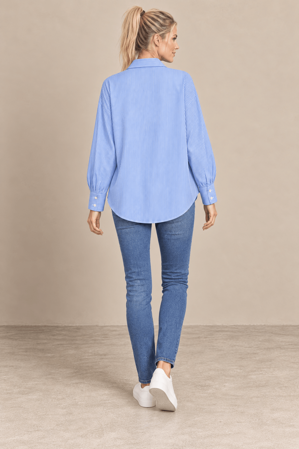 Camisa Cashia Elisa azul vista de espalda, con rayas verticales finas y bajo redondeado, combinada con vaqueros.