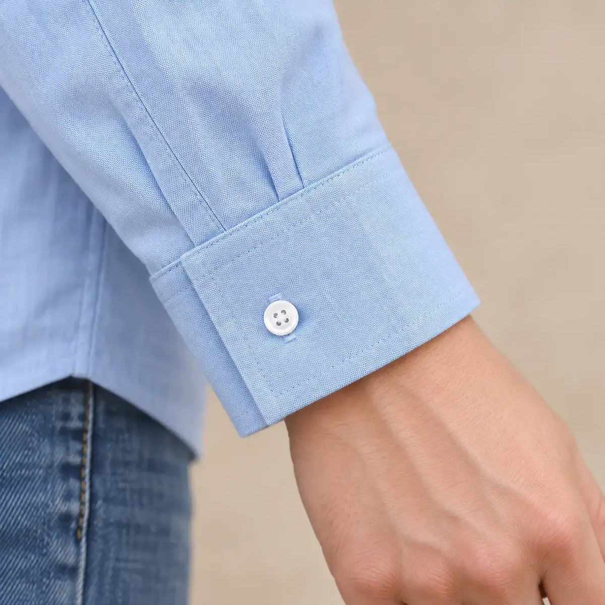 Detalle del puño azul cerrado de la Camisa Cashia Irene, con botón blanco y costuras visibles.