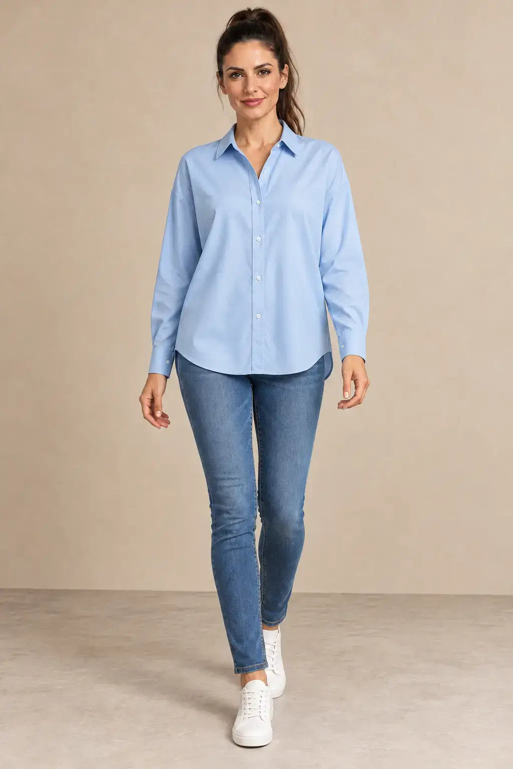 Camisa Cashia Irene azul claro con cuello camisero y puños cerrados, vista frontal en modelo morena con vaqueros.