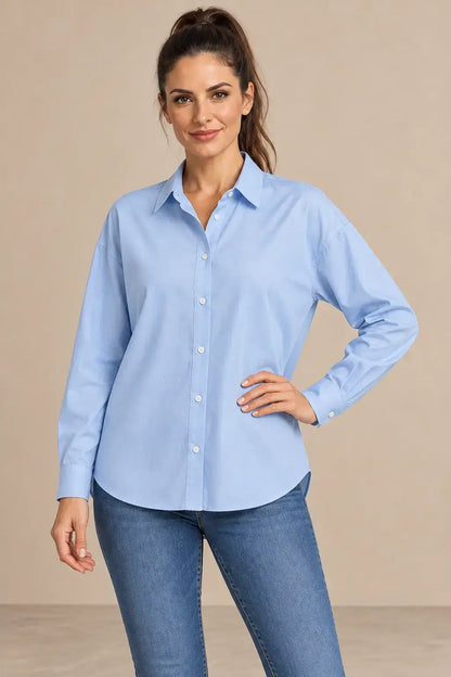 Modelo morena con Camisa Cashia Irene azul claro en medio plano superior, con botones blancos y puños cerrados.