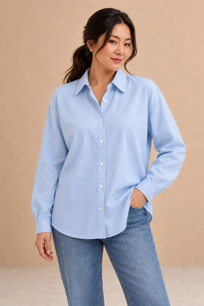 Camisa Cashia Irene azul claro, talla L, en modelo asiática con pelo recogido, puños cerrados y vaqueros.