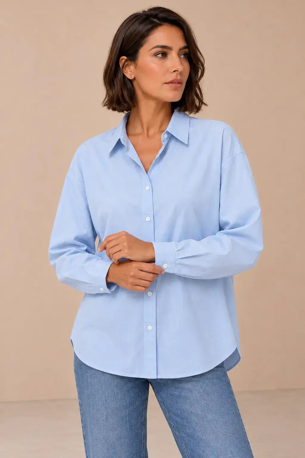 Camisa Cashia Irene azul claro, talla M, en modelo morena con corte bob, mostrando los puños abotonados.