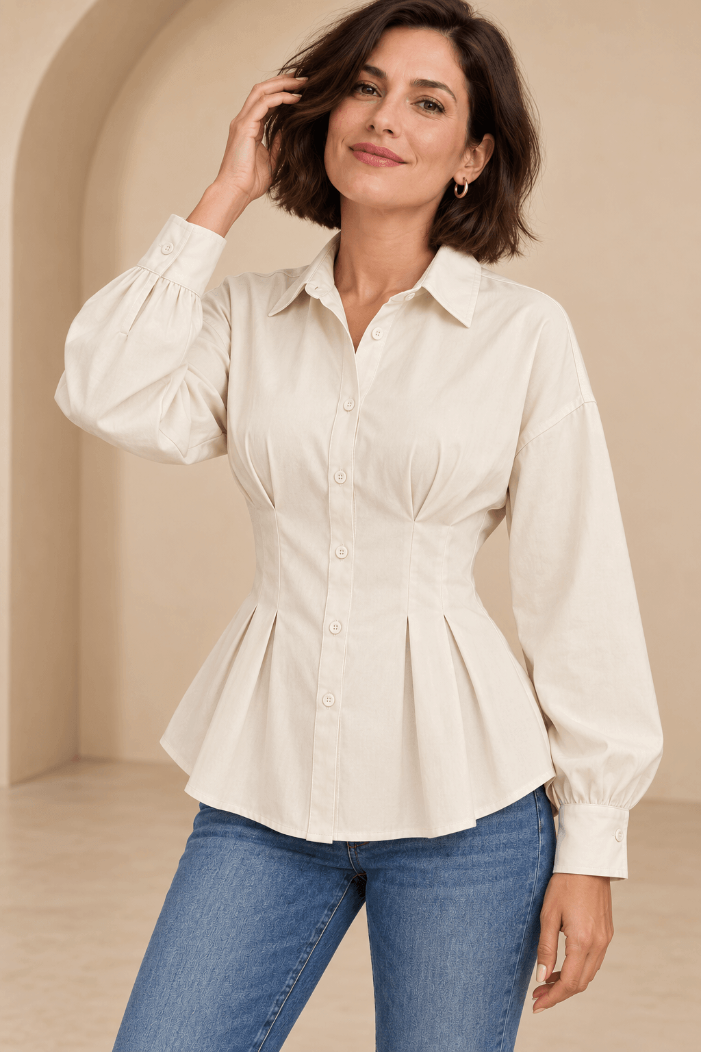 Camisa Cashia Vera cruda en talla M, sobre modelo Cashia de cabello bob, con tejanos y una mano junto al pelo.