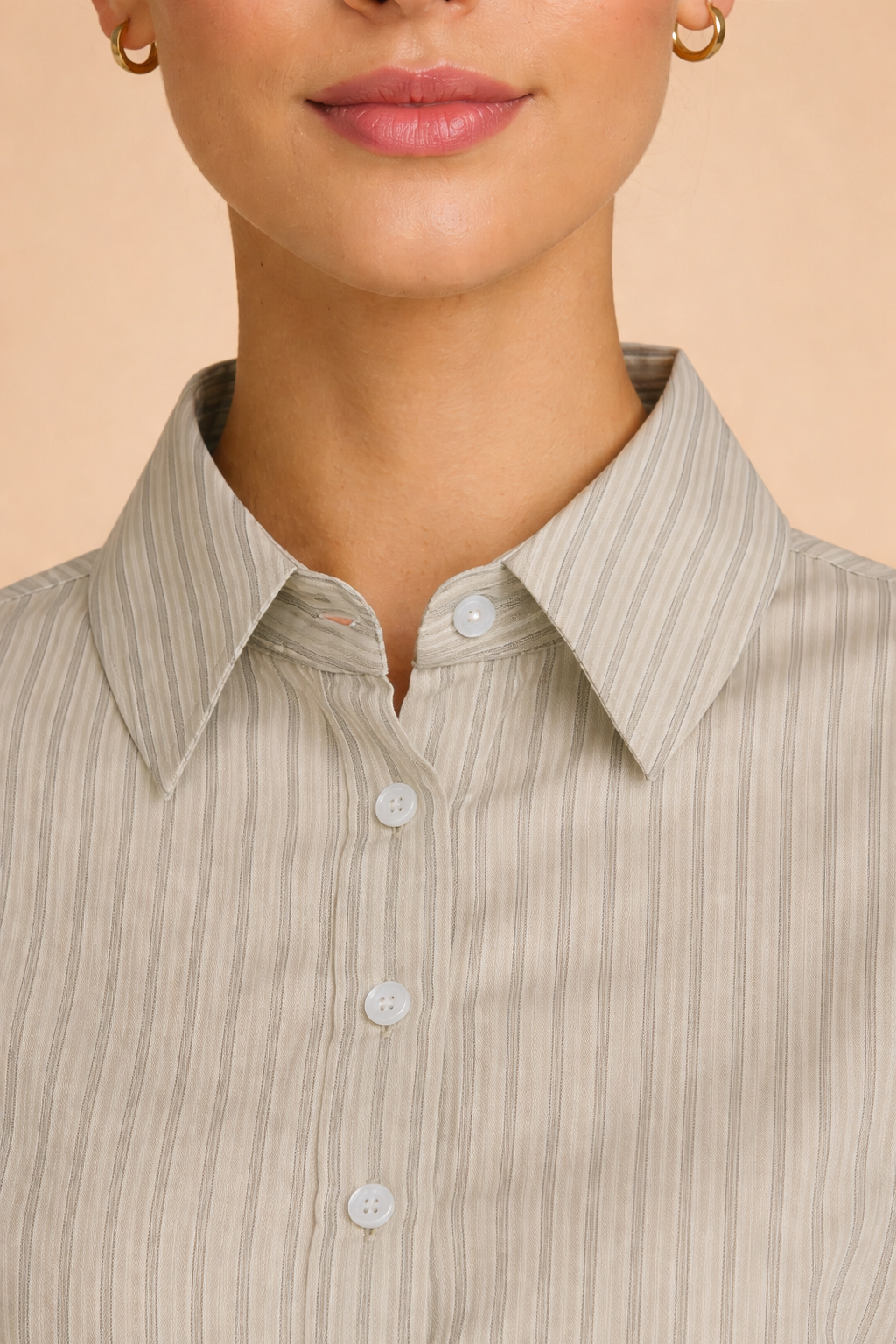 Detalle del cuello de la camisa Cashia en tono beige con rayas verticales, cuello clásico con botones frontales, fondo nude.