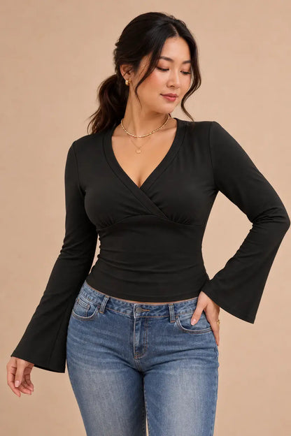 Camiseta escote cruzado mangas acampanadas en color negro con jeans, estilo elegante y moderno.
