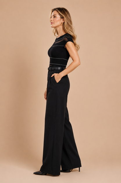 Vista de perfil de la Camiseta Cashia Ferrara negra con transparencias sutiles y pantalón negro wide leg.