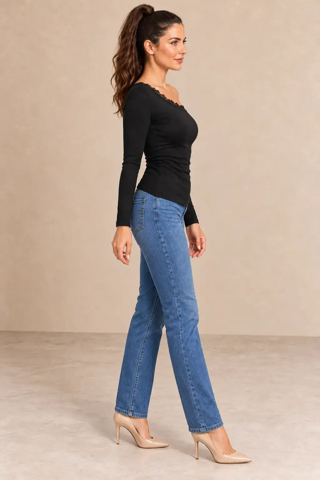 Camiseta negra manga larga encaje asimétrico combinada con jeans azules y tacones, vista lateral.