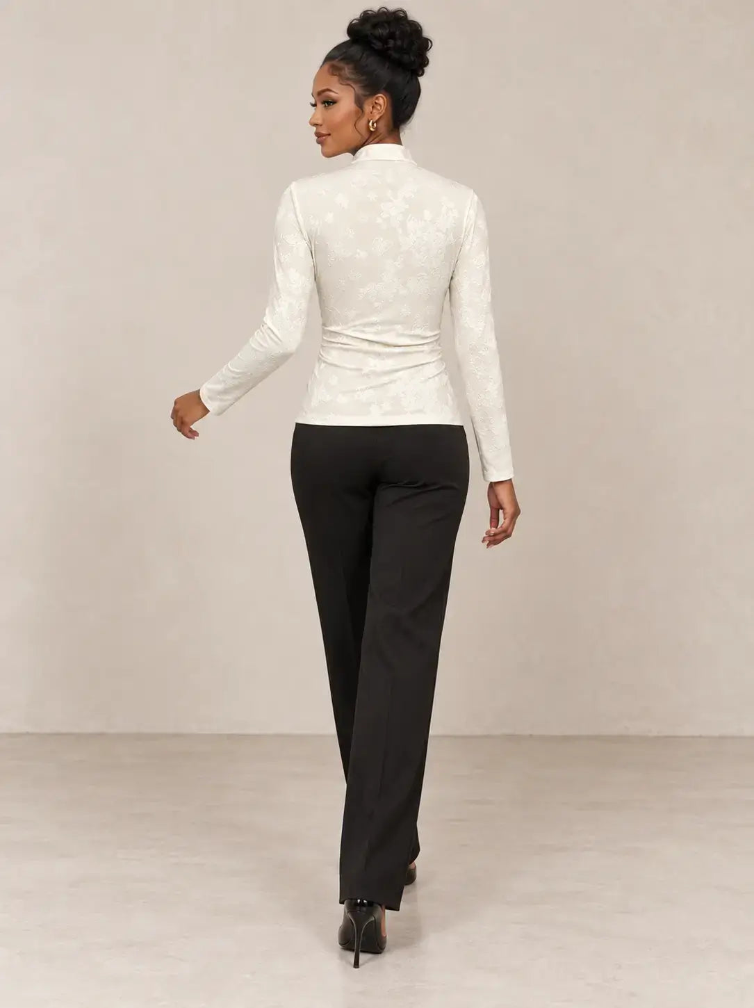 Mujer de espaldas vistiendo camiseta mujer cuello mao detalle floral en color blanco y pantalones negros.