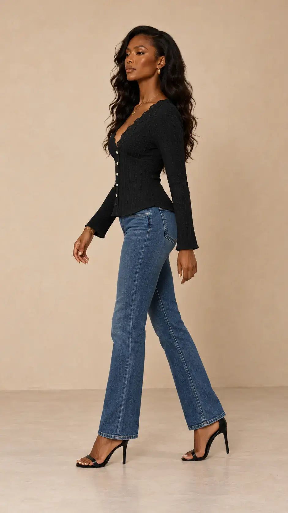 Modelo luciendo una camiseta larga encaje botones negra y jeans, posando con estilo.