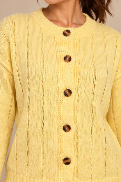 Detalle de los botones marrones jaspeados y la tapeta del cárdigan Cashia Boj amarillo sobre modelo.