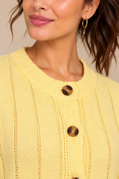 Detalle del cuello redondo de canalé del cárdigan Cashia Boj amarillo sobre modelo.