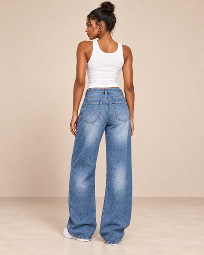 Pantalón Cashia Denim 303 en azul denim claro con cordón en cintura y bajo roto, vista trasera con modelo S y camiseta blanca de tirantes.