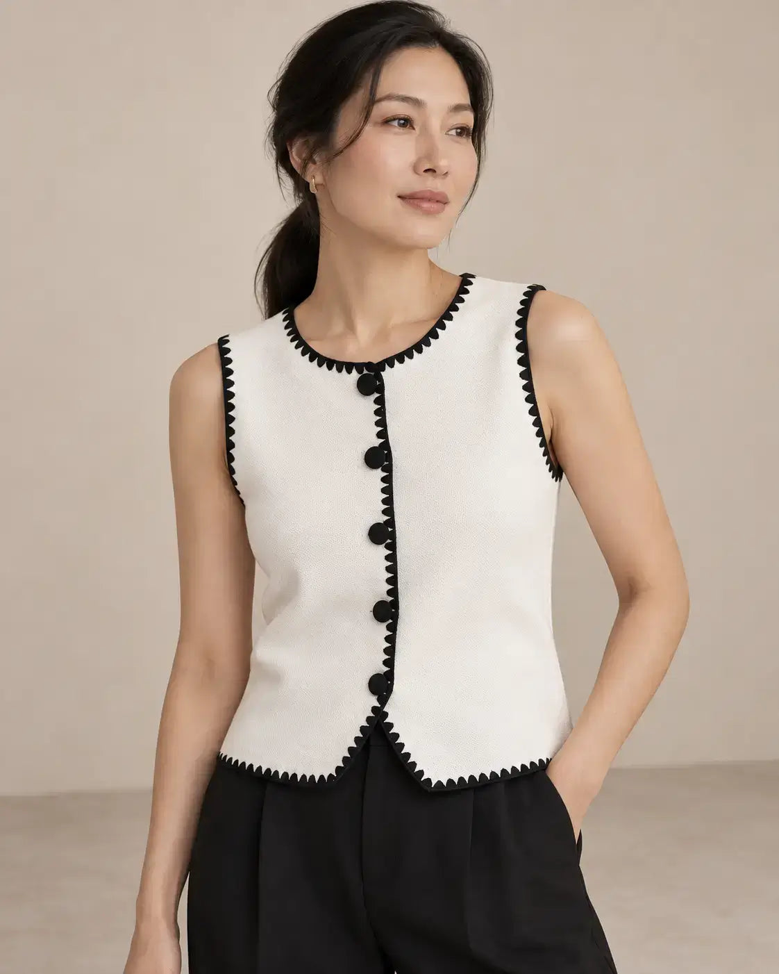 Chaleco Cashia Elegance blanco con ribetes negros y cinco botones, talla L, en modelo asiática con coleta baja y pose de tres cuartos.