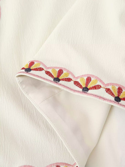 Detalle del bajo con bordado decorativo en el Chaleco Cashia Nice crema con acabado ondulado en tonos rosa, amarillo y negro