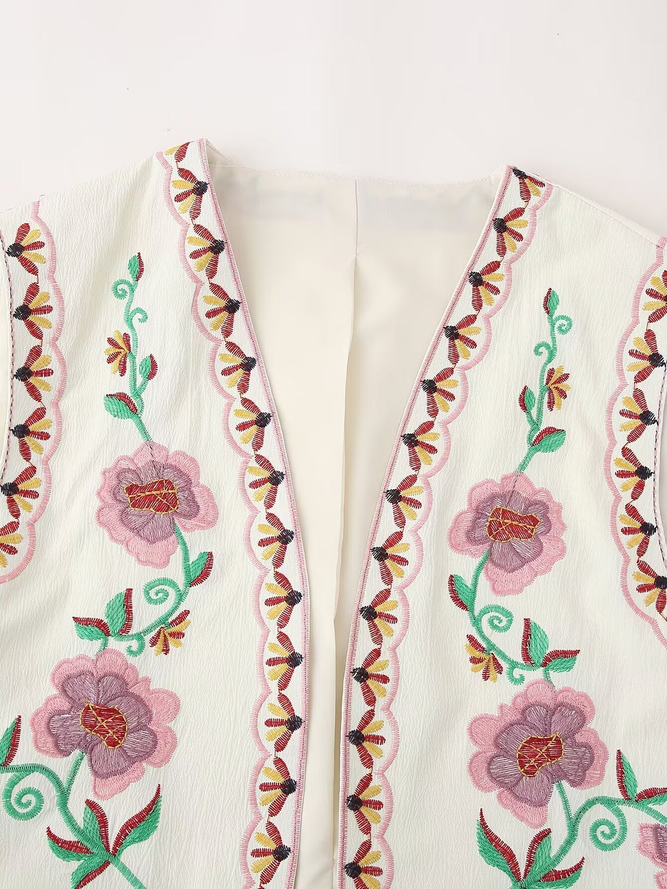 Detalle frontal del Chaleco Cashia Nice con bordado floral en tonos rosa y verde sobre tejido crema con acabado artesanal