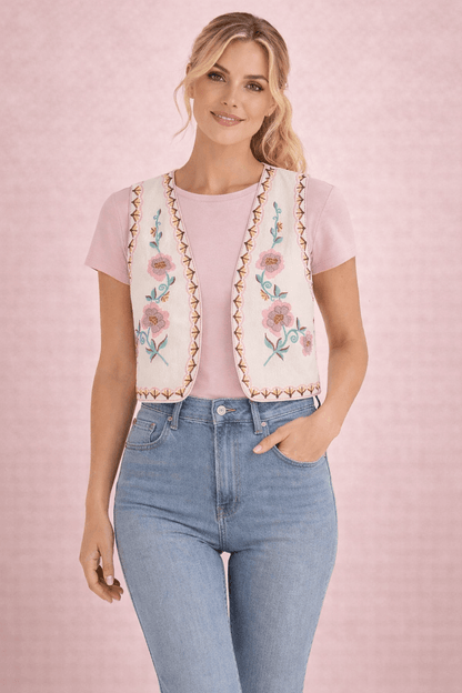 Modelo rubia con el chaleco floral crema abierto sobre camiseta rosa y jeans, vista frontal de medio plano