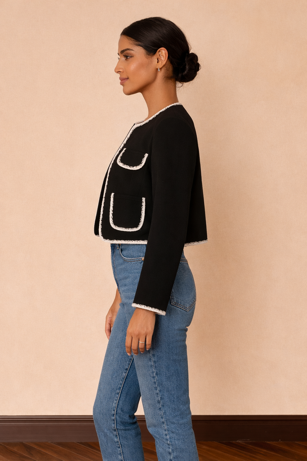 Chaqueta corta Cashia Lady en color negro con ribetes blancos, vista lateral de perfil combinada con top blanco y jeans azul de tiro alto