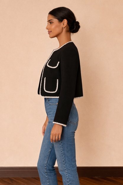 Chaqueta corta Cashia Lady en color negro con ribetes blancos, vista lateral de perfil combinada con top blanco y jeans azul de tiro alto