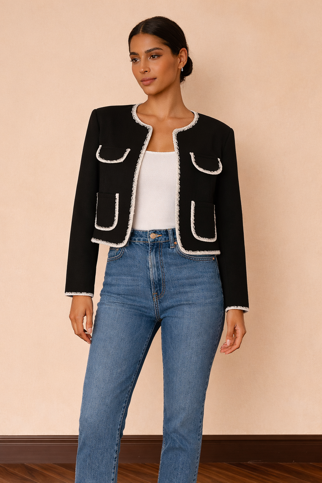 Chaqueta corta Cashia Lady en color negro con ribetes blancos combinada con top blanco básico y jeans azul de tiro alto, vista frontal cuerpo entero.