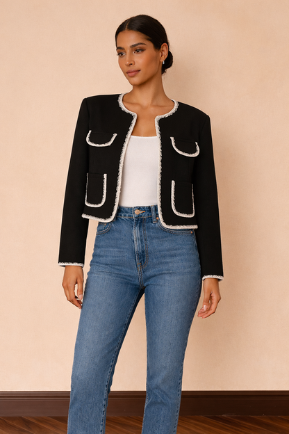 Chaqueta corta Cashia Lady en color negro con ribetes blancos combinada con top blanco básico y jeans azul de tiro alto, vista frontal cuerpo entero.