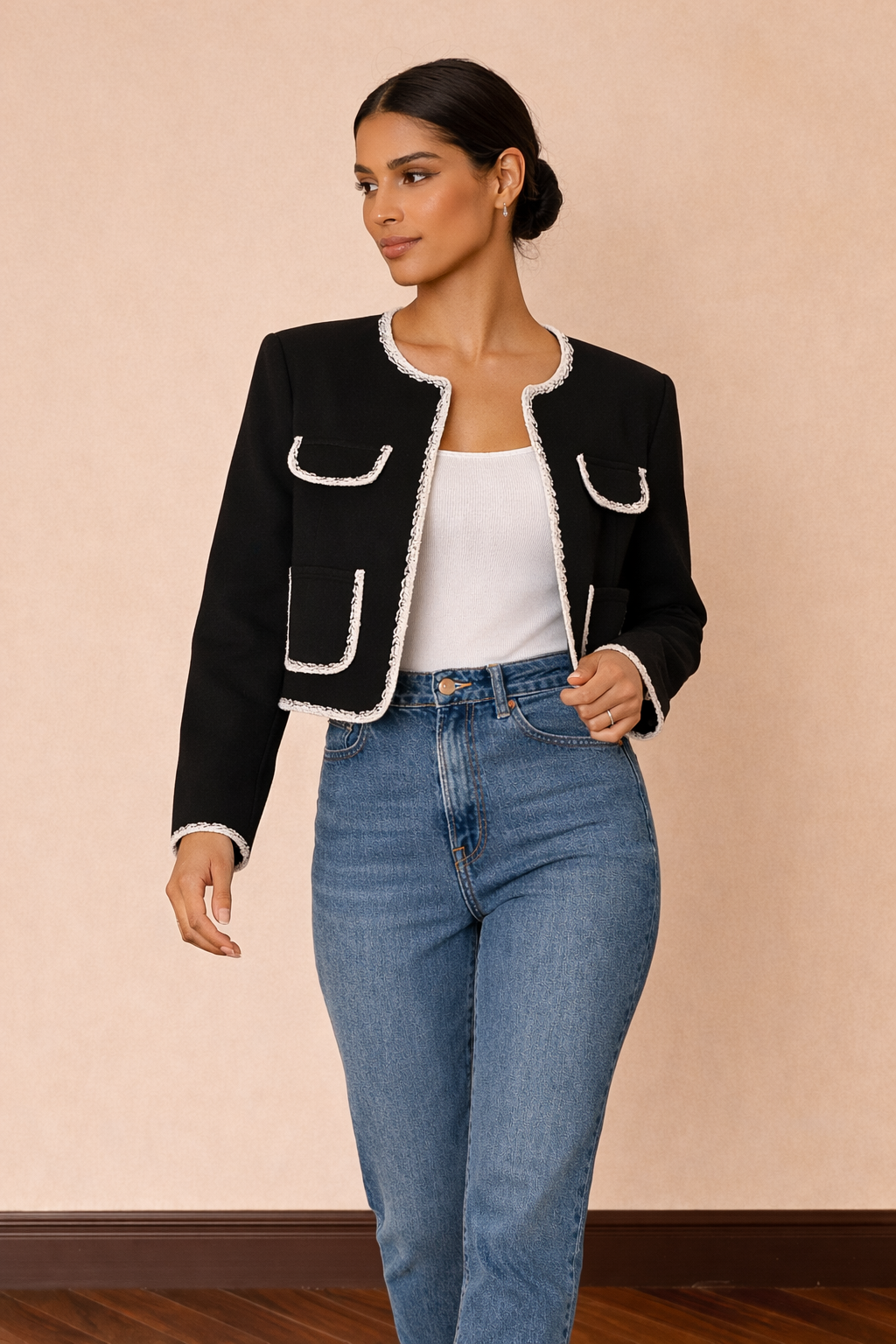 Chaqueta corta Cashia Lady en color negro con ribetes blancos, imagen en movimiento combinada con top blanco básico y jeans azul de tiro alto.
