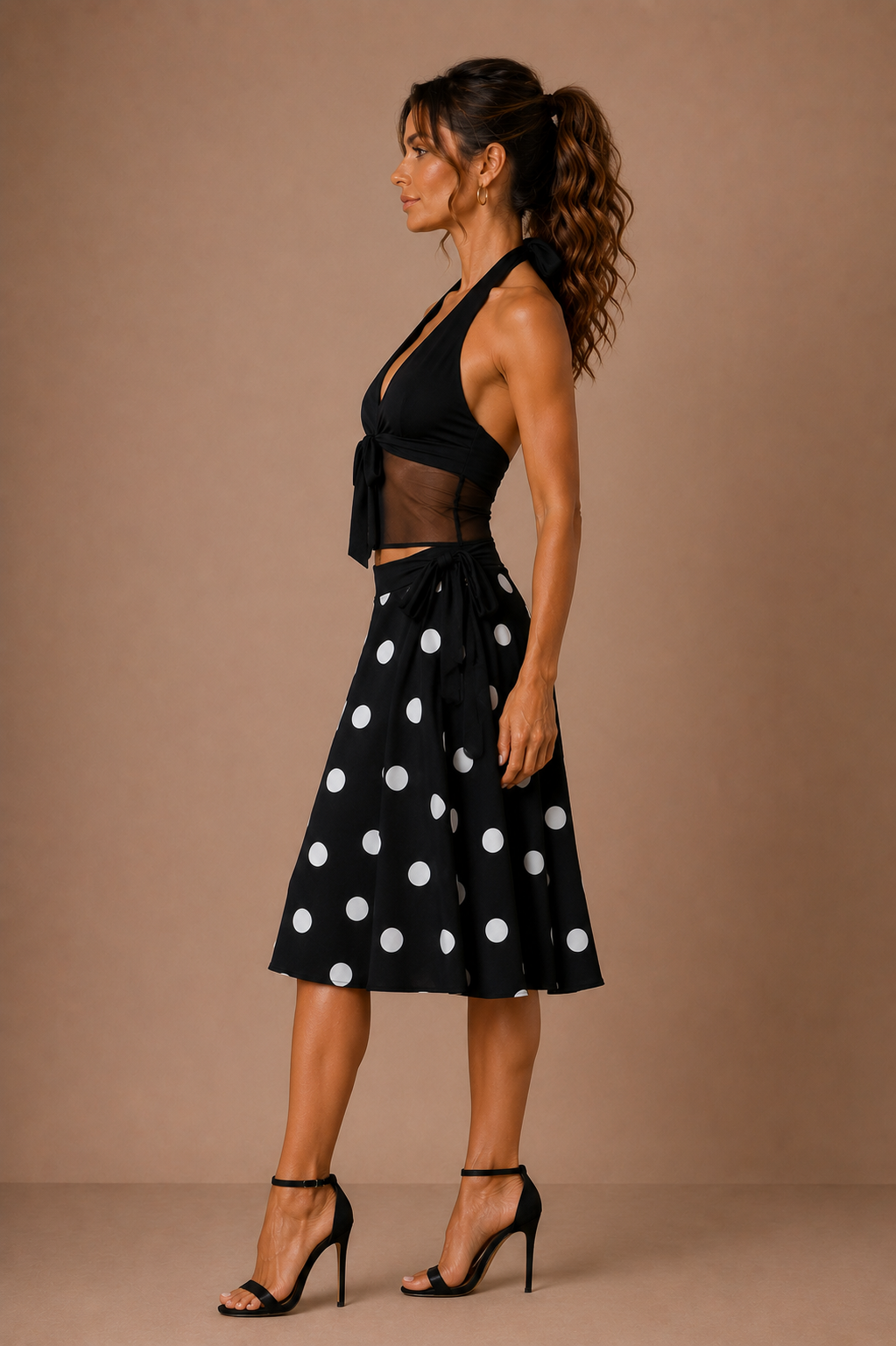 Vista de perfil del Conjunto Cashia Livorno negro con top halter, panel transparente y falda de lunares blancos con vuelo.