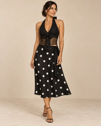 Conjunto Cashia Livorno negro de dos piezas en modelo talla M, top halter con lazada y transparencias y falda midi de lunares blancos.