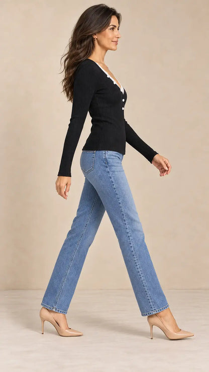 Mujer caminando con jersey de mujer con encaje y botones, jeans y tacones, resaltando el estilo sofisticado.
