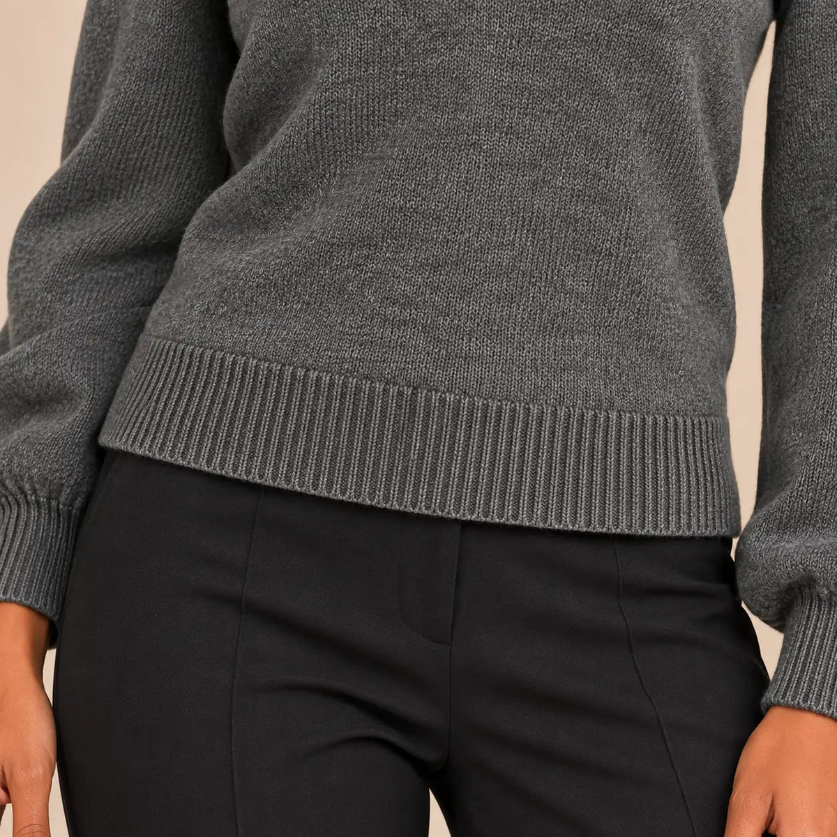 Primer plano sobre modelo del bajo de canalé del jersey Cashia Arolla gris, combinado con pantalón negro de vestir.