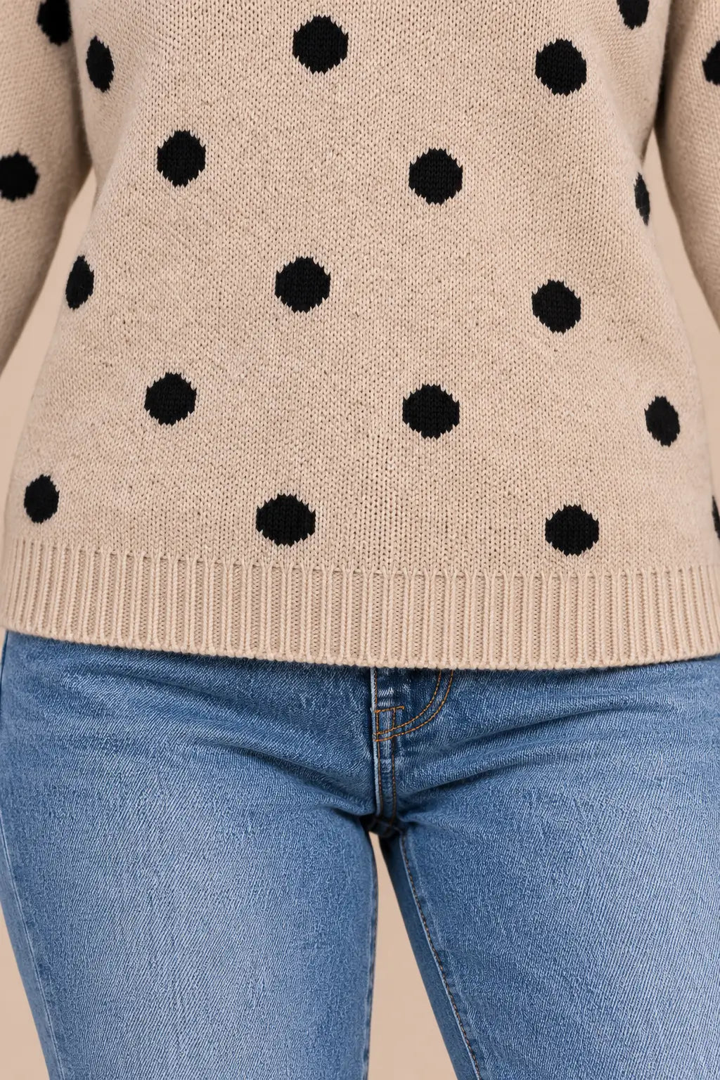 Detalle sobre modelo del bajo recto de canalé del jersey Cashia Haya beige con lunares negros, combinado con vaqueros.
