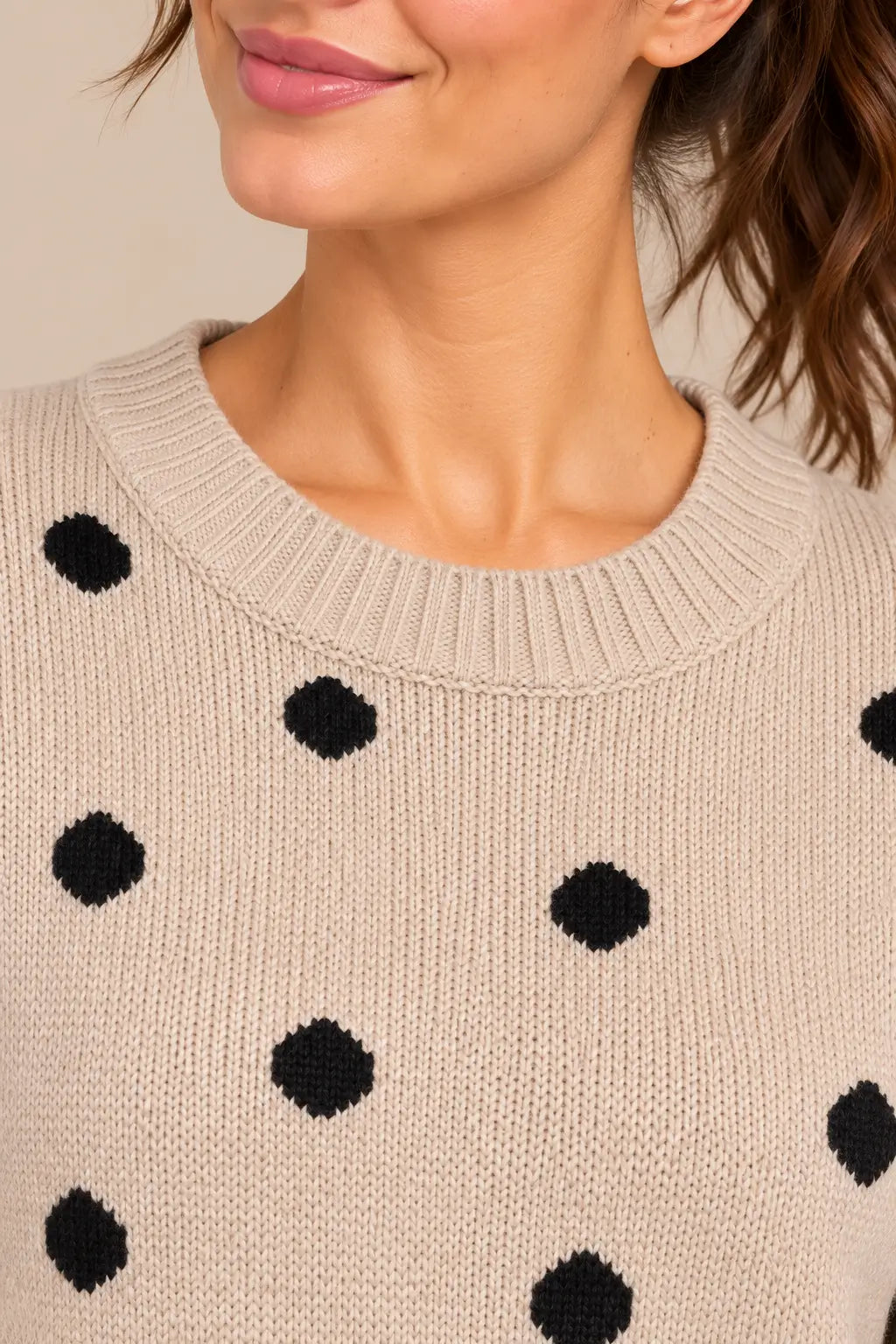 Primer plano sobre modelo del cuello redondo de canalé del jersey Cashia Haya beige con lunares negros.