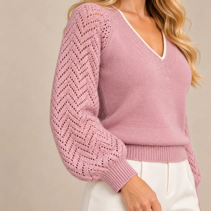 Detalle de la manga del jersey Cashia Saja rosa empolvado sobre modelo rubia, con calado geométrico en zigzag y puño de canalé.