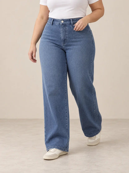Pantalón Cashia Denim 401 denim medio, talla 2XL, medio plano inferior sobre modelo, con tiro alto y pernera ancha.