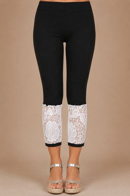 Detalle frontal del Pantalón Cashia Denim Encaje negro con panel de encaje floral blanco en el bajo sobre fondo nude Cashia