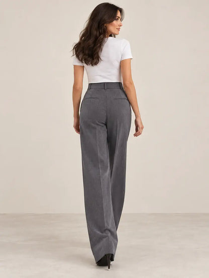Mujer usando pantalón de mujer tiro alto pinzas con pierna amplia en color gris, vista trasera.
