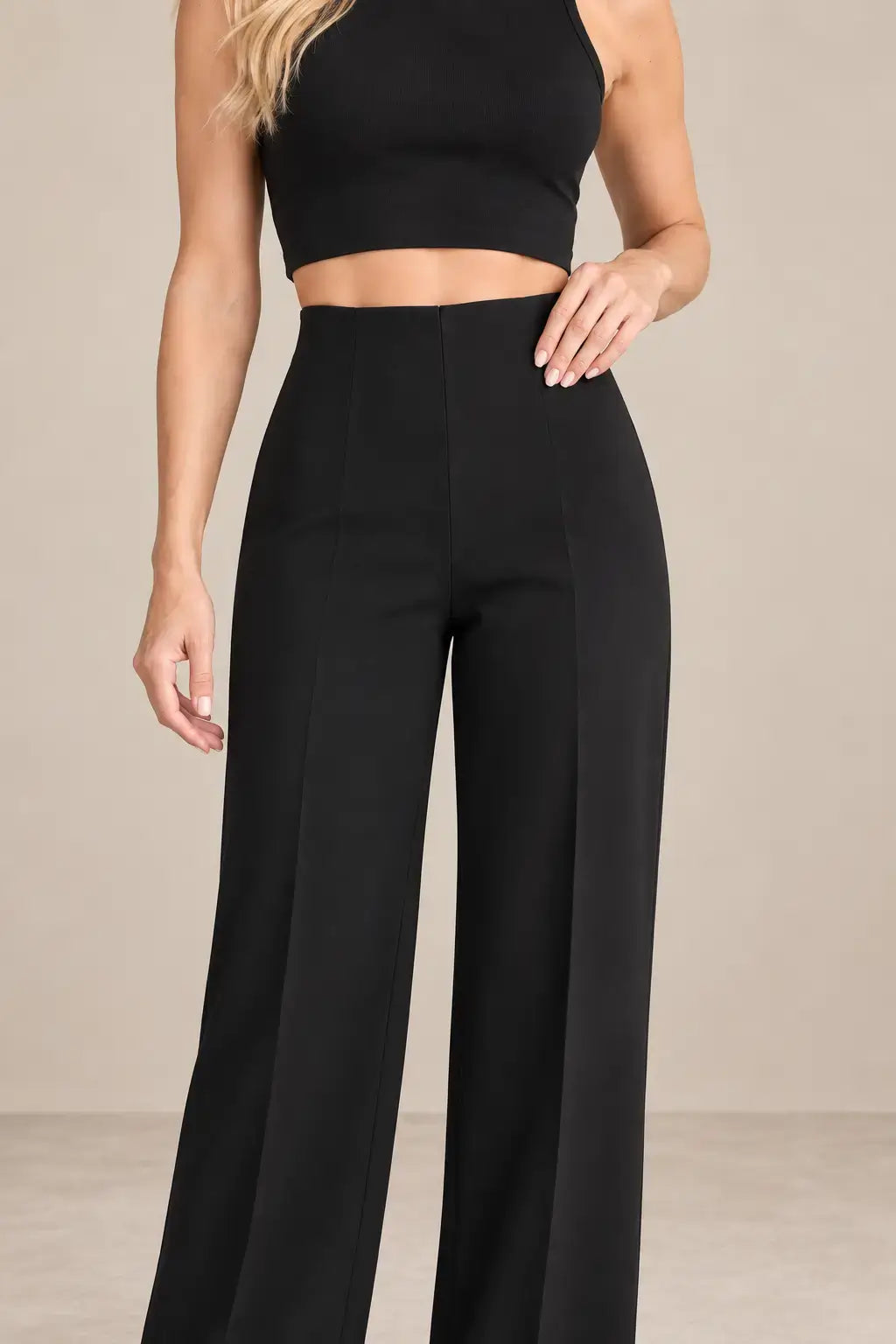 Mujer usando pantalón de mujer tiro alto pierna amplia en color negro con top corto.