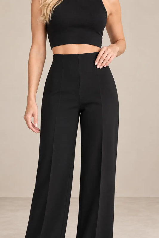 Mujer usando pantalón de mujer tiro alto pierna amplia en color negro con top corto.
