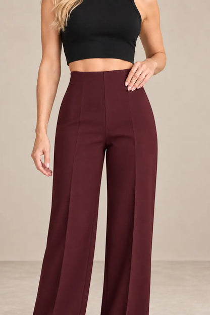Mujer usando pantalón de mujer tiro alto pierna amplia en color burdeos, combinado con un top negro.