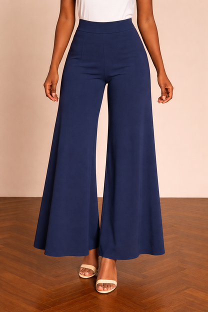 Pantalón Cashia Granada azul marino en medio plano inferior, con cintura alta y pierna ancha de caída fluida hasta el bajo, sobre fondo nude y suelo de madera en espiga.