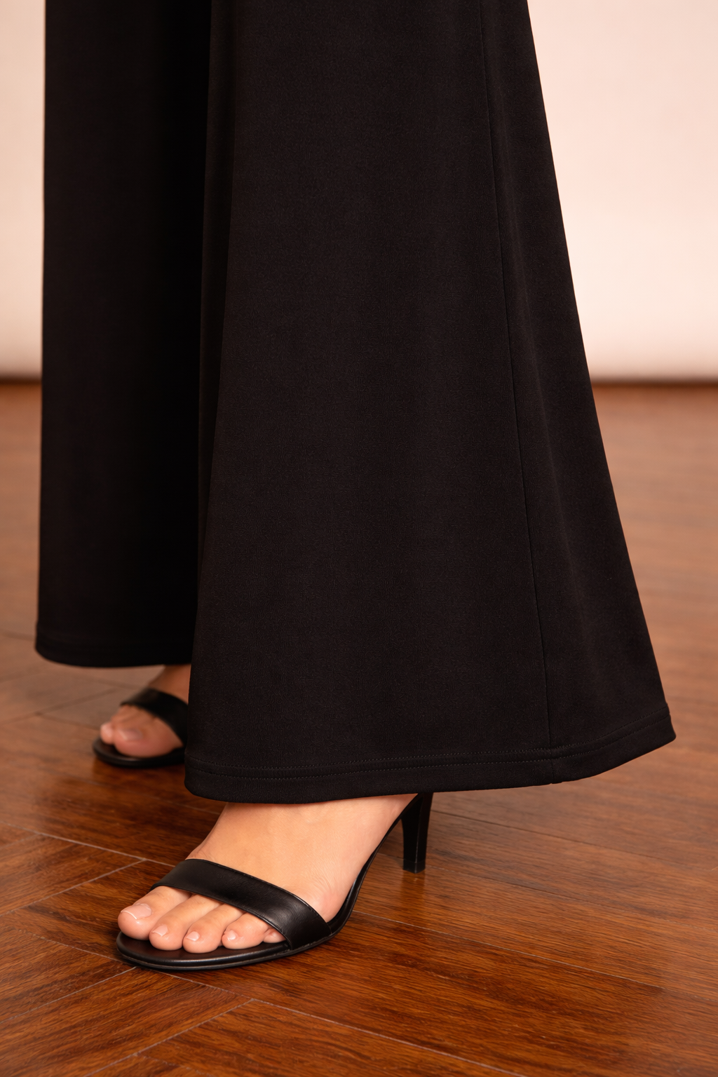 Detalle del bajo del Pantalón Cashia Granada negro, con acabado limpio y caída amplia sobre suelo de madera.