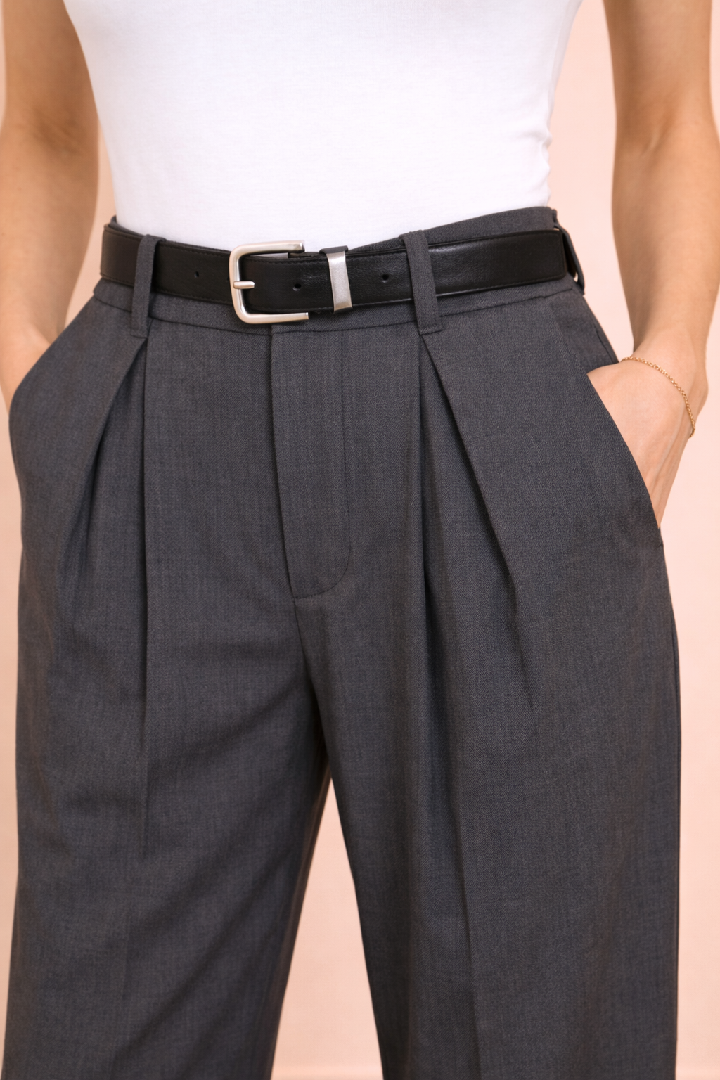 Detalle de las pinzas delanteras del Pantalón Cashia Sevilla gris de tiro alto, mostrando la estructura de la cintura y el acabado del tejido sobre fondo nude.